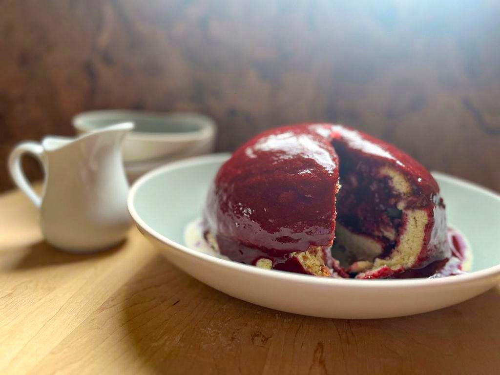 Red Berries-Soaked Cake in a dish with a creamer nearby