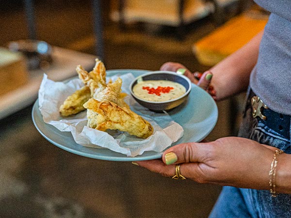 Server with plate of food at Emmer and Rye's 90/90 dinner event