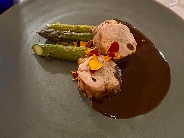 A plate of food with asparagus, pork and mole sauce